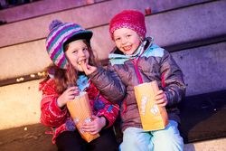 Zwei Kinder essen Popcorn auf den Tribünen der Eissporthalle