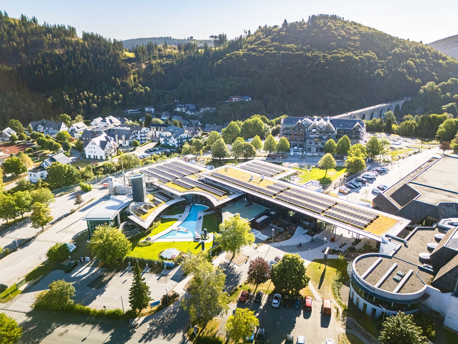 Drohnenaufnahme vom Lagunen-Erlebnisbad, auf den Dächern sind die Solaranlagen zu sehen und im Vordergrund die Parkplätze sowie das Außenbecken vom Solebad.