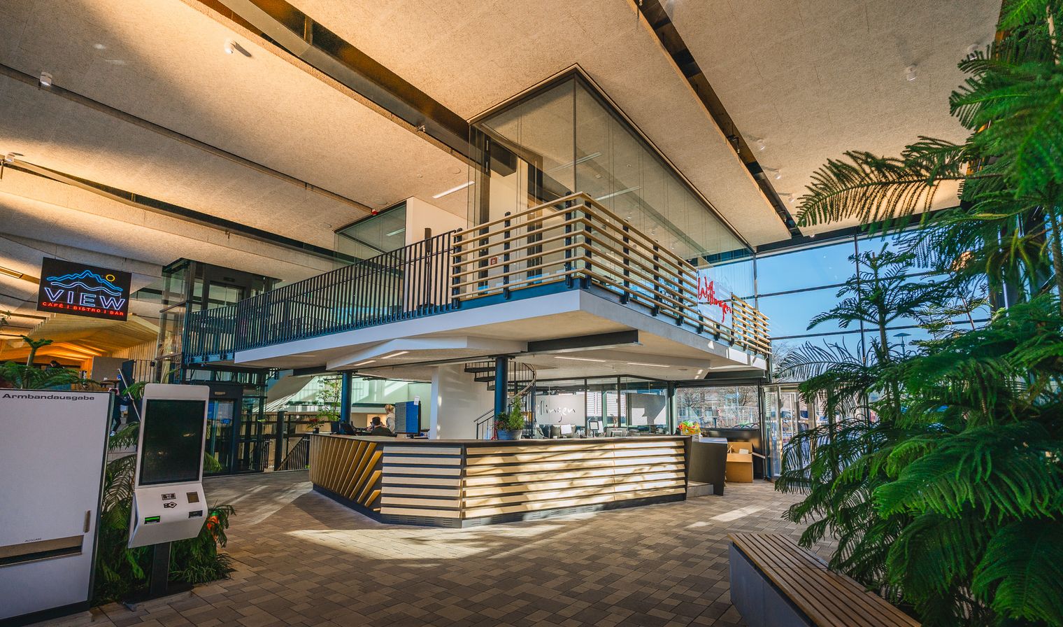 Foyer des Lagunen-Erlebnisbades, im EG der holzvertäfelte Kassenbereich, darüber ein Bürotrakt zu erkennen. Im Vordergrund der Kassenautomat.