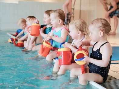 Kleinkinder mit Wasser-Gießkannen beim Körperteile gießen.