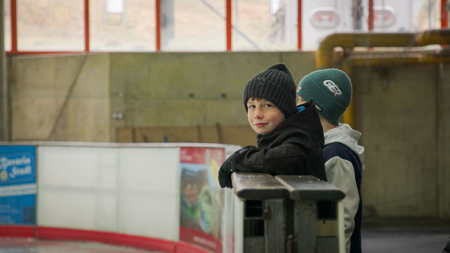 Zwei Kinder stehen an der Eisbande.