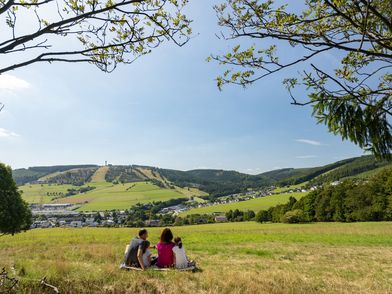 Familie auf einer Wiese inmitten der Natur mit Blickrichtung Ettelsberg